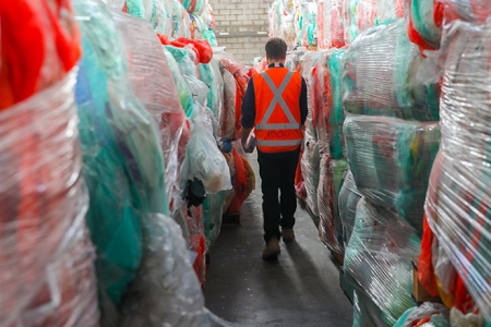 man walking between stockpiles of soft plastics