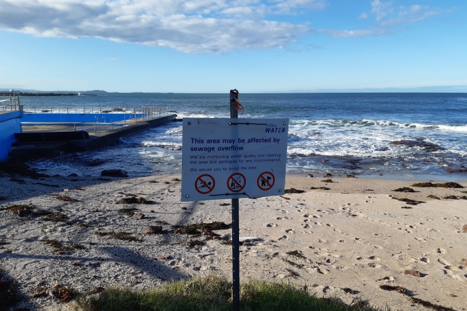 Shellharbour Beach with a Sydney Water sign warning the area may be affected by sewage overflow.