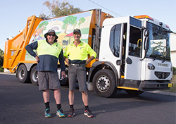 two workers beside garbage truck