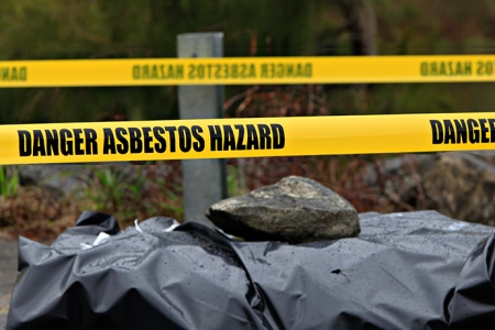 warning tape around a plastic covered pile of asbestos