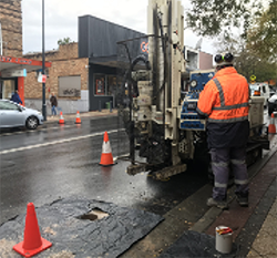 worker preparing a drill rig on a street
