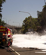 fire truck spraying a burnt out truck with foam