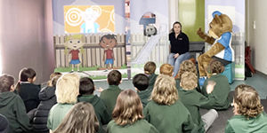 Lead Ted character presenting to children sitting on a floor in a classroom