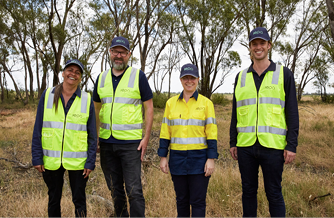 staff members in the field - two women and two men wearing hi-vis vests 