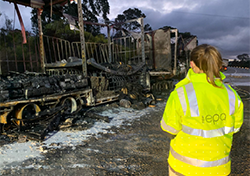 EPA officer in hi vis at the site of a burnt out truck