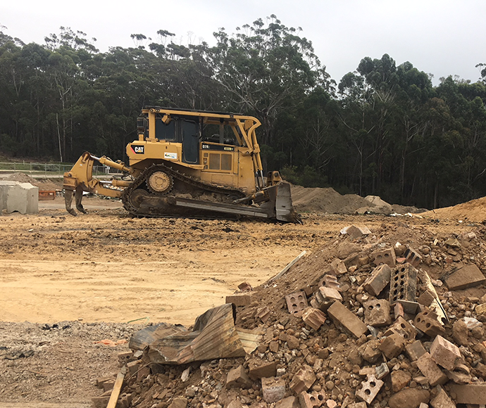 bulldozer with piles of soil and bricks