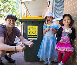 Man and two girls beside a paper recycling bin