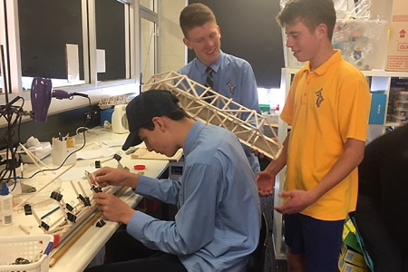 three students working on a model recycling cage