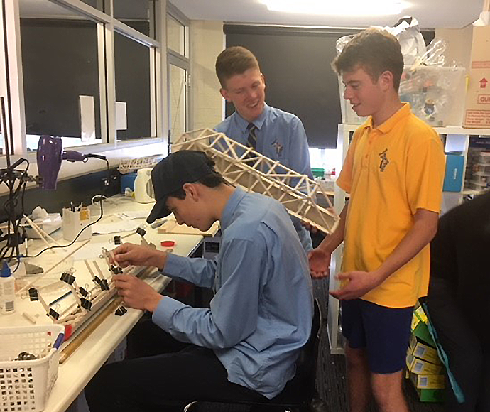 three students working on a model recycling cage