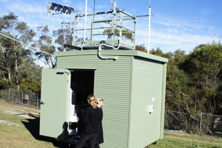 two women outside an air monitoring equipment shed