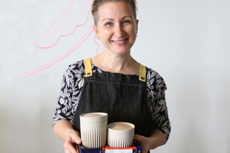 woman holding two disposable coffee cups