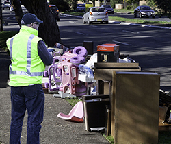 An inspector wearing hi-vis checking a pile of illegally dumped material