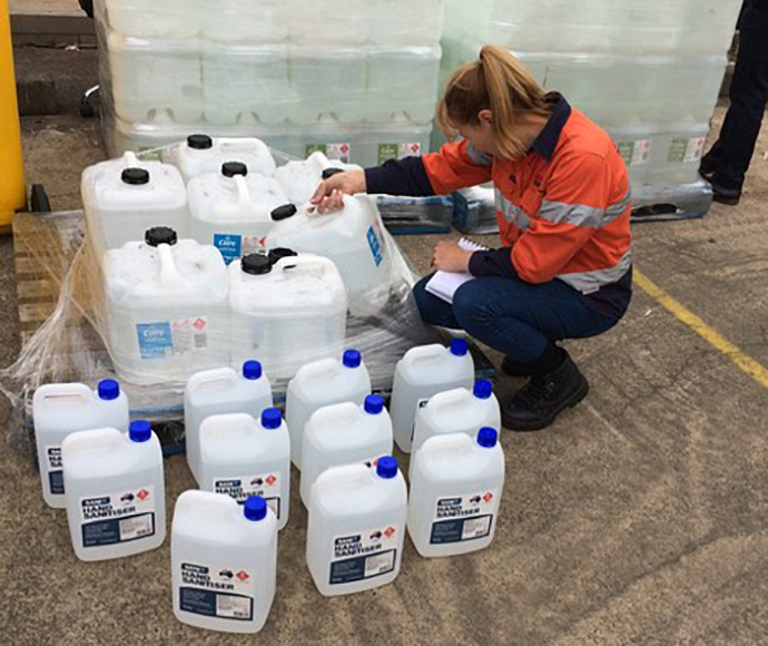 worker checking large containers of hand sanitiser