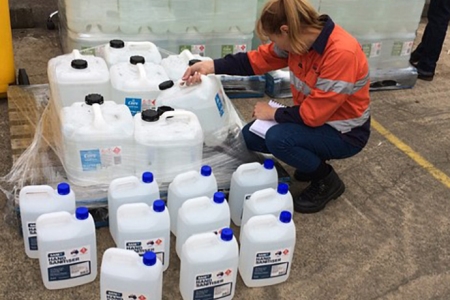 worker checking large containers of hand sanitiser
