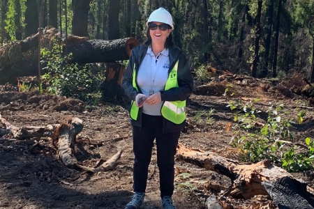 Tracy Mackey wearing hard hat and hi-vis vest in the forest
