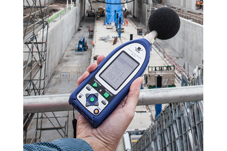 EPA officer with hand-held noise monitor above construction site