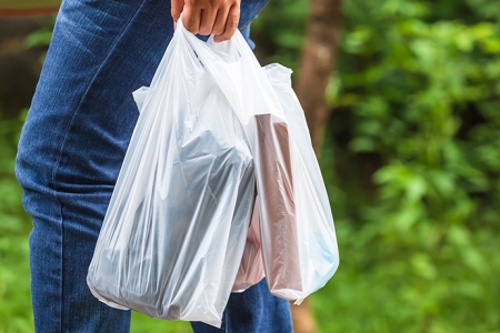 man carries groceries in single use plastic bags