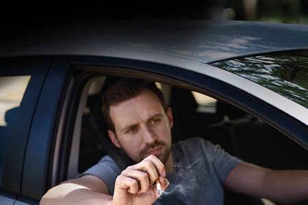 man throwing cigarette butt out of car window 