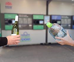 hands holding bottles at a return and earn machine