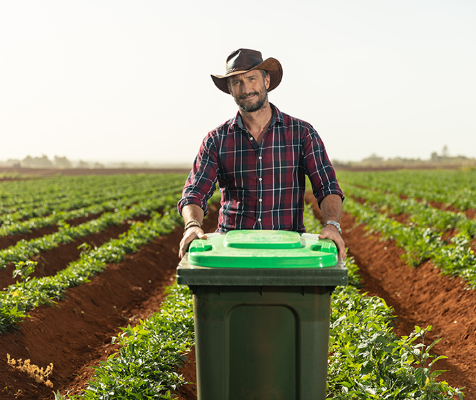 , farmer shows green lid bin with food waste compost to help with his crops 