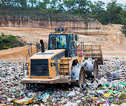 dozer moves plastics and waste in landfill