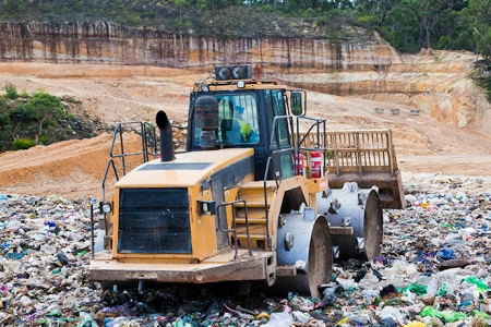 dozer moves plastics and waste in landfill