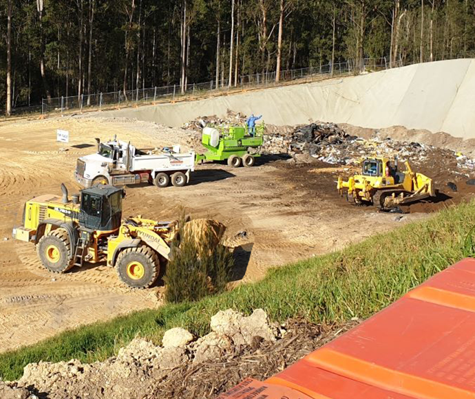 a bulldozer and trucks at work at a council landfill site