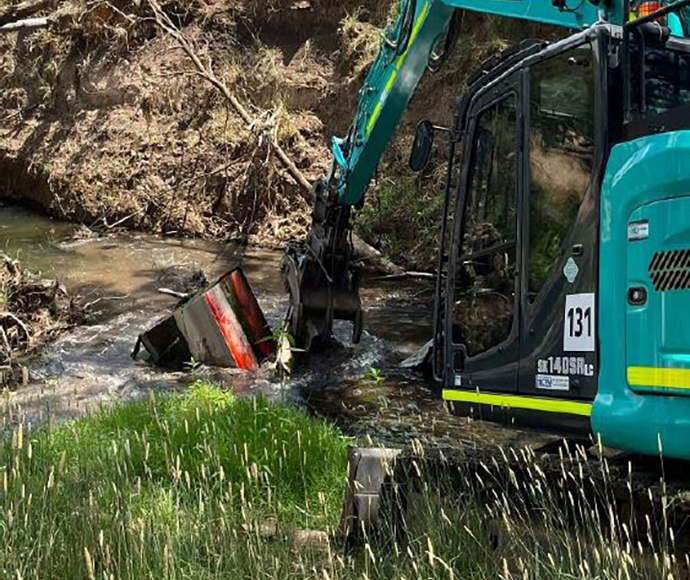 an excavator removing rubbish from a waterway