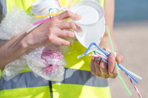 Person holding a variety of littered single-use plastics