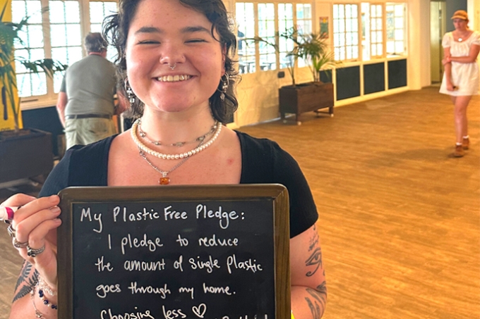 Young woman holding OzGREEN pledge - I pledge to reduce the amount of single-use plastic goes through my home