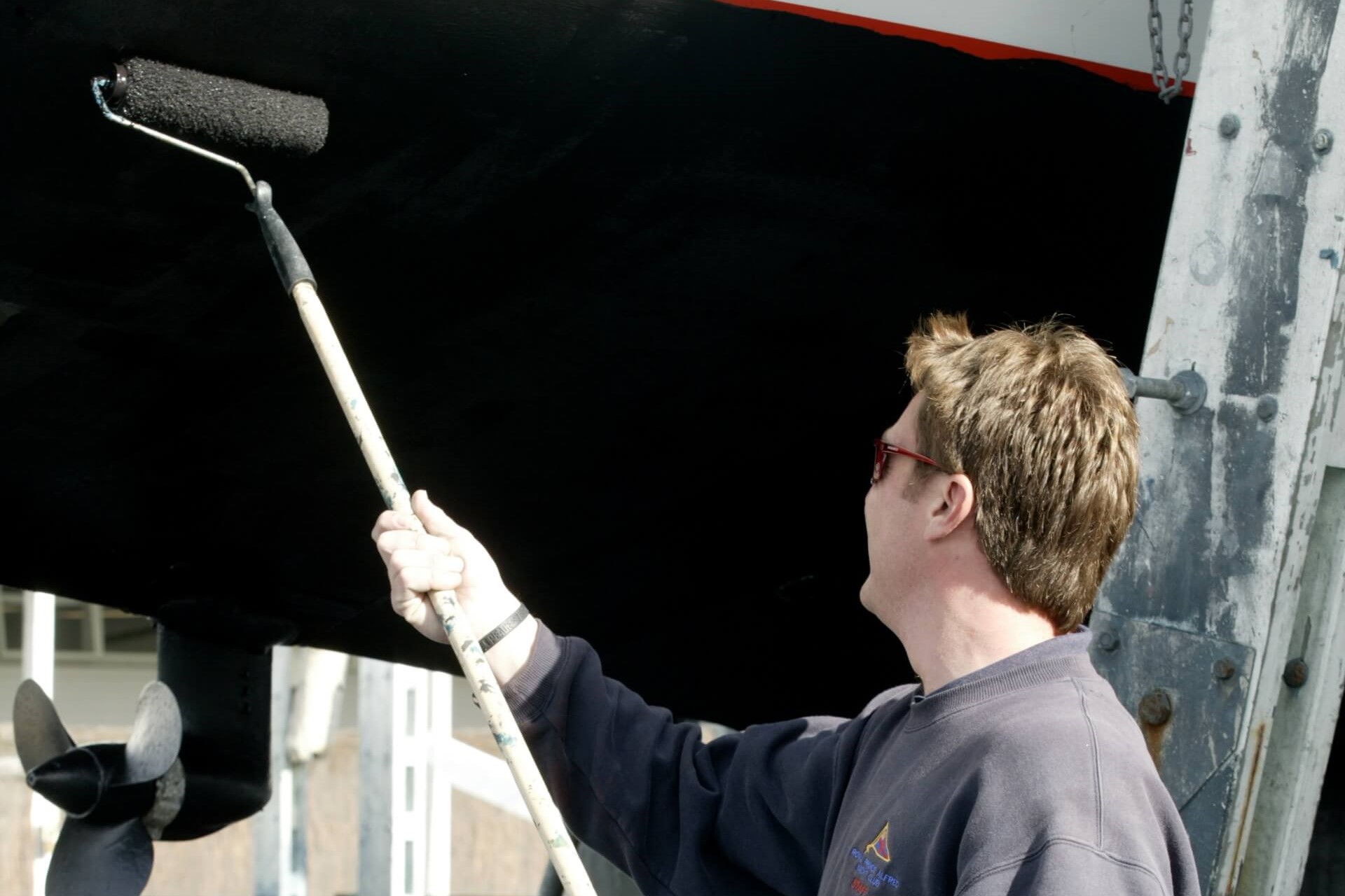 Person applying reduced VOC paint to a boat hull